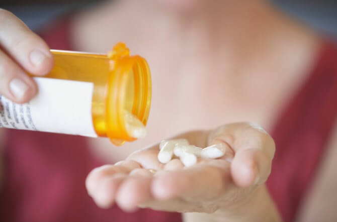 Close-up of a person's hands holding a bottle of pills
