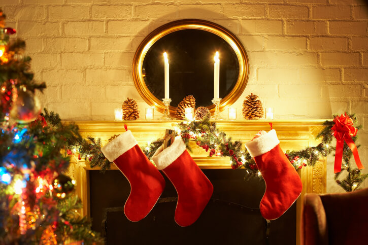 Fireplace mantle decorated with stockings and candles