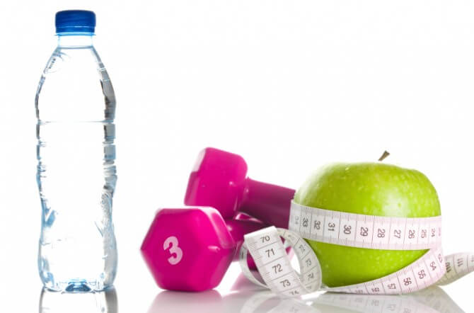 dumbbells with measuring tape around apple and bottle
