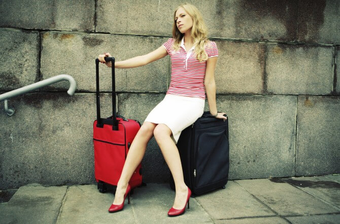 woman sitting on her luggage and waiting