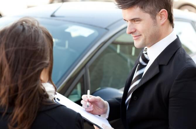 Car dealer writing down a woman's information