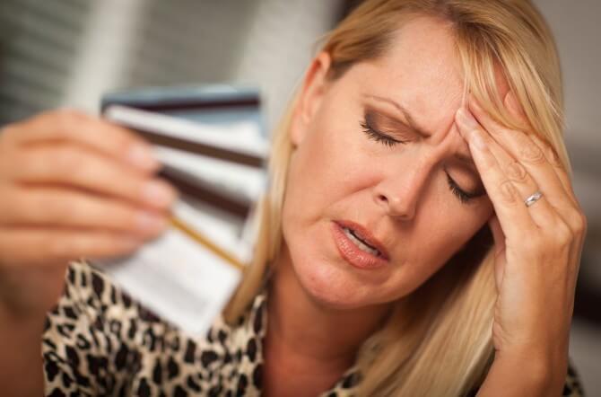 Woman holding credit cards and stressed