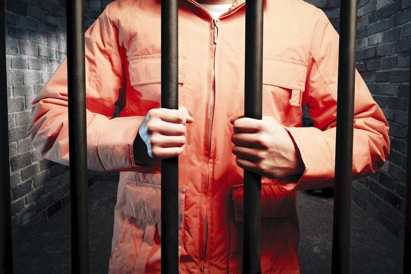 Man in orange jumpsuit in jail