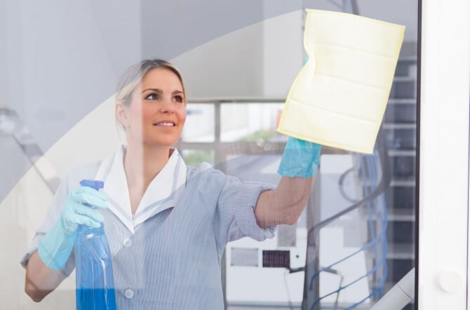 woman in uniform cleaning window
