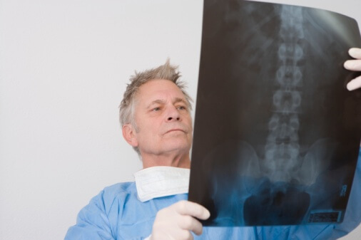 Senior medical practitioner stands with xray
