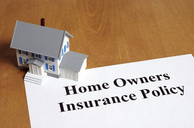 homeowners insurance policy paper with house paperweight