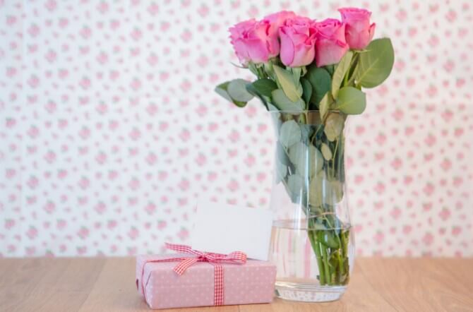 Bunch of pink roses in vase with pink gift and blank card
