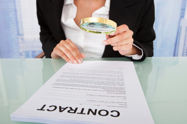 Businesswoman Scrutinizing Contract With Magnifying Glass