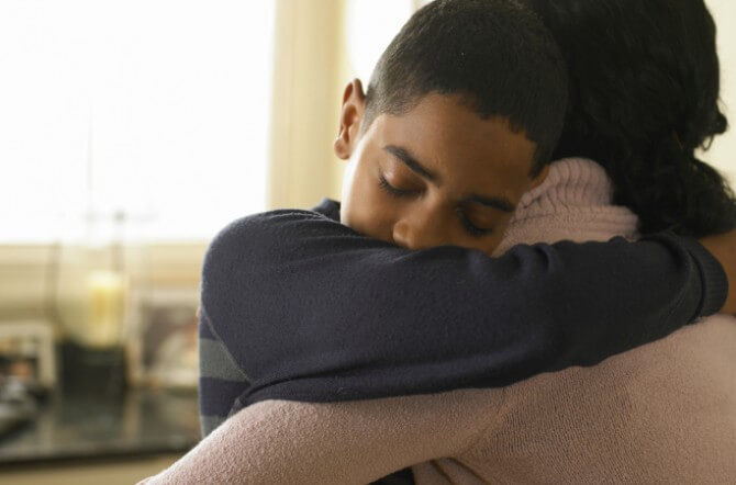 Boy (12-13) hugging mother at home