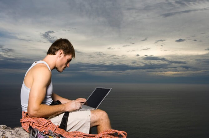 Man Using Laptop on a Cliff