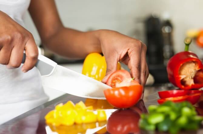 African American womans hand slicing a tomatoe