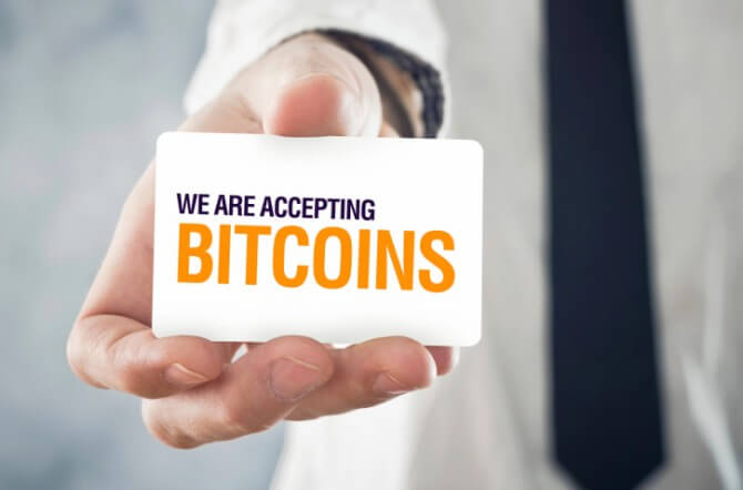 Businessman holding card with title WE ARE ACCEPTING BITCOINS